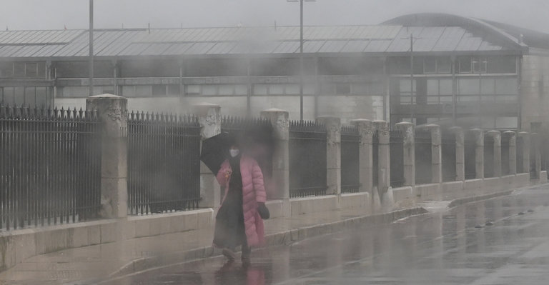 Una persona bajo la lluvia camina en las inmediaciones del Palacio de Festivales. / HARDY