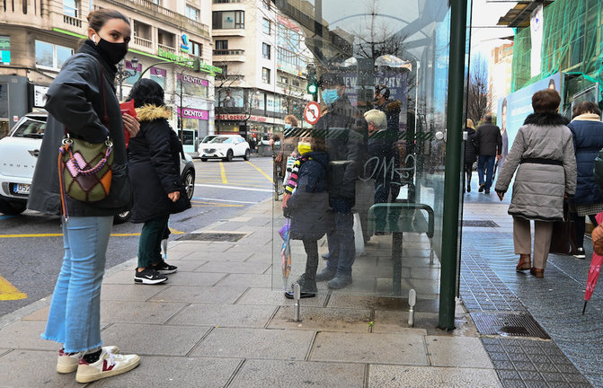 Varias personas con mascarilla en una parada de autobús en el centro de Santander. / Hardy