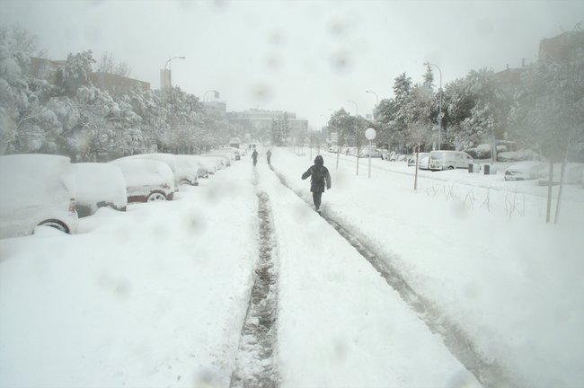 Algunas personas caminan por una calzada completamente cubierta de nieve de una calle en Alcobendas, Madrid (España) a 9 de enero de 2021
