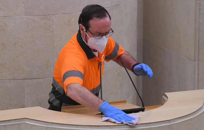 Un trabajador del Parlemento limpia la tribuna durante la sesión. / HARDY