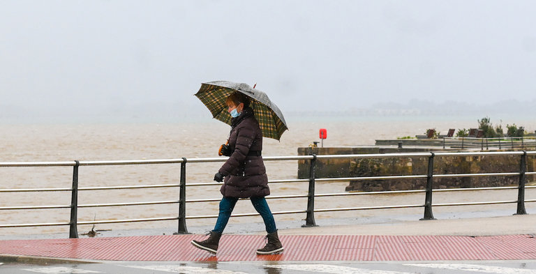 Una persona con paraguas por las inmediaciones de la bahía de Santander. / Hardy