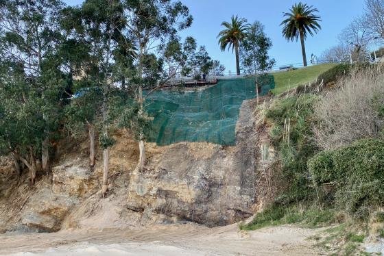 César Díaz explica que los operarios siguen colocando la malla anti-erosión y la triple torsión en los dos argayos y retirando el material acumulado en el borde de la playa.