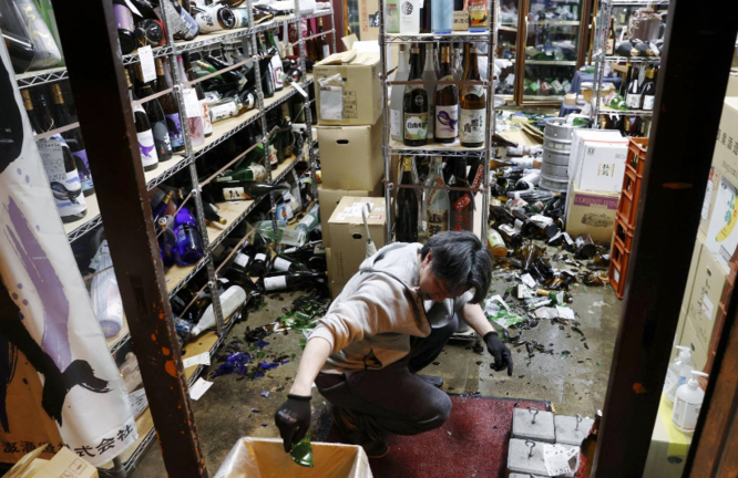 El gerente de una licorería en la ciudad de Fukushima limpia tras el terremoto del sábado por la noche.