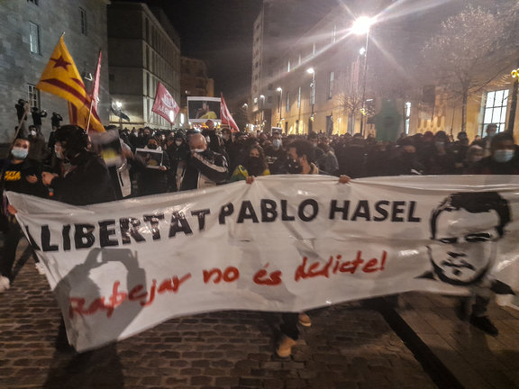 Varias personas sujetan una pancarta en la que se lee: `Libertat Pablo Hasel´ en una concentración de más de 2.000 personas en rechazo al encarcelamiento de Pablo Hasel por las calles de Girona, Cataluña (España), a 16 de febrero de 2021