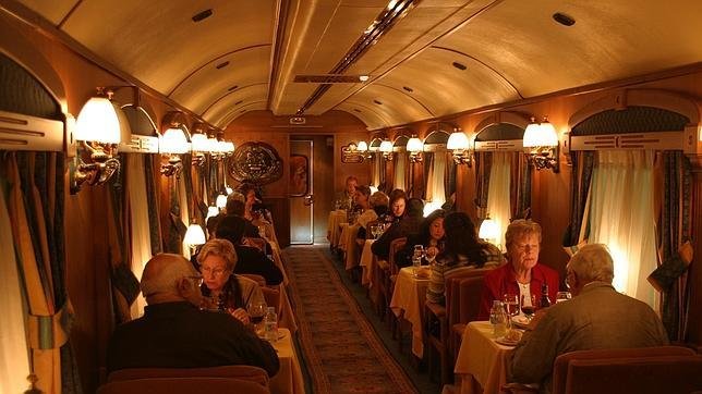 Varias personas sentadas en mesas en el interior de uno de los vagones del Transcantábrico. /Archivo