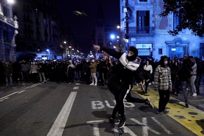 Manifestantes lanzan objetos esta noche frente a la comisaría de Vía Layetana, en el centro de Barcelona, en una nueva manifestación por la libertad de Pablo Hasel, después de cinco días consecutivos de protestas que han finalizado con enfrentamientos con los Mossos d'Esquadra y daños a bienes públicos y privado. EFE/Alejandro García