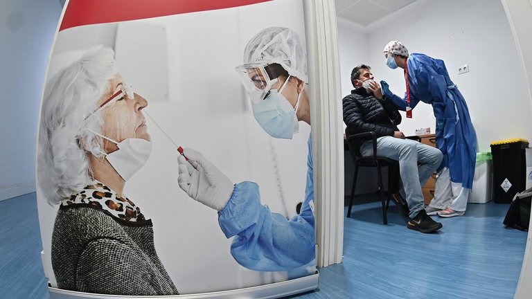 Una trabajadora sanitaria toma una muestra de saliva para un test de antígenos a un trabajador en la estación de Atocha en Madrid, este lunes. EFE/ Fernando Villar