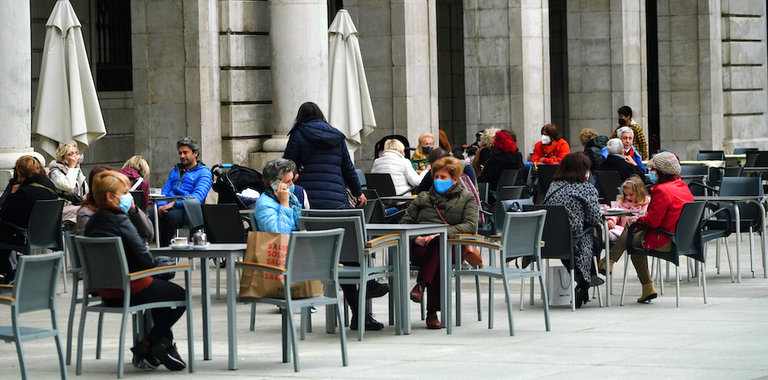 Varias personas con mascarilla disfrutan de la terraza de un establecimiento de hostelería en la plaza Porticada de Santander. / HARDY
