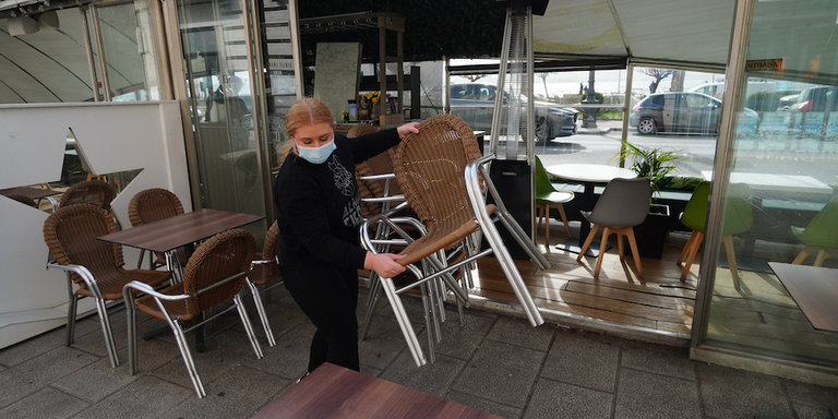 Una trabajadora de la hostelería prepara las sillas de su terraza en el Paseo Pereda de Santander. / HARDY