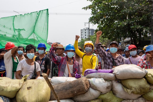 Protesters raise their fists from behind of the sand bags that block the road during the demonstration against the junta in Yangon on March 14, 2021. Thousands of people took the streets of Yangon on the 42nd day of the protest against a military coup and demanded the release of Aung San Suu Kyi. Myanmar's Military detained State Counsellor of Myanmar Sung San Suu Kyi on 1st of February, 2021 and declared a state of emergency while seizing the power in the country for a year after losing the election against the National League for Democracy.