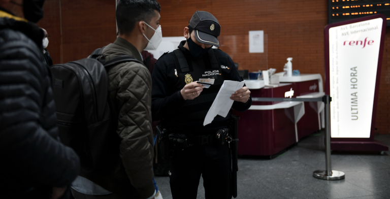 Un agente de Policía Nacional pide documentación a un pasajero en la estación de Atocha, en Madrid (España), a 18 de marzo de 2021. / Óscar Cañas / Europa Press