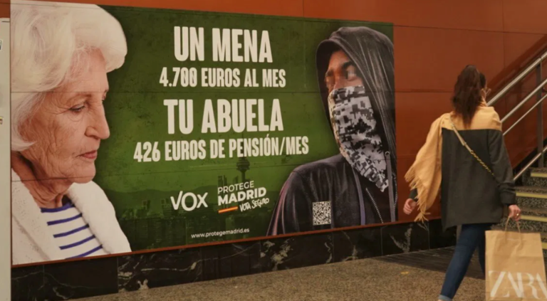 Una mujer pasa por delante del cartel electoral de Vox denunciado por posible delito de odio.