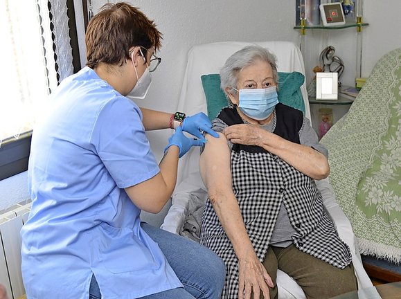 Un enfermera mide las constantes a una señora en su domicilio tras ser vacunada. / efe