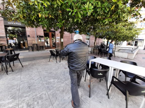 Una persona atraviesa una zona de terraza en la plaza Baldomero Iglesias de Torrelavega. / S. DÍAZ