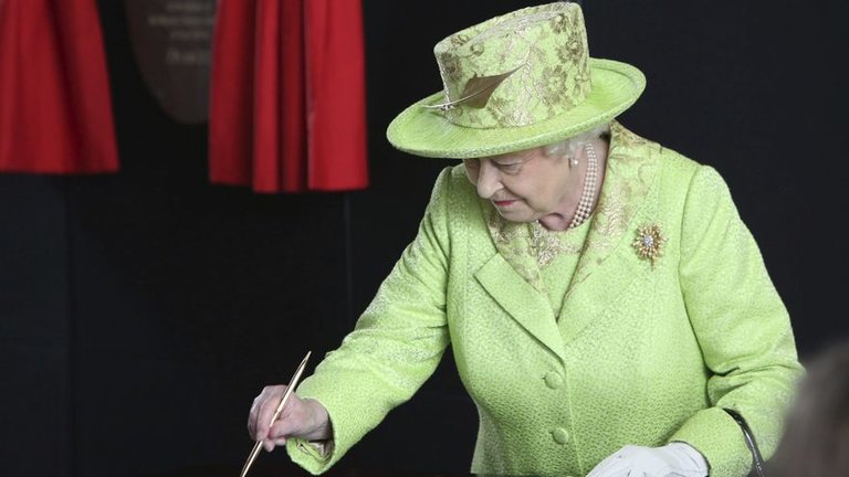La reina Isabel II de Inglaterra firmaba en el libro de visitantes a su salida de la exposición del Titanic en Belfast, Irlanda del Norte, durante una visita a laregión británca en 2012. EFE/Paul McErlane/Archivo