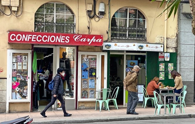 Varias personas caminan por delante de dos establecimientos abiertos durante la tarde de ayer en Santander. / HARDY