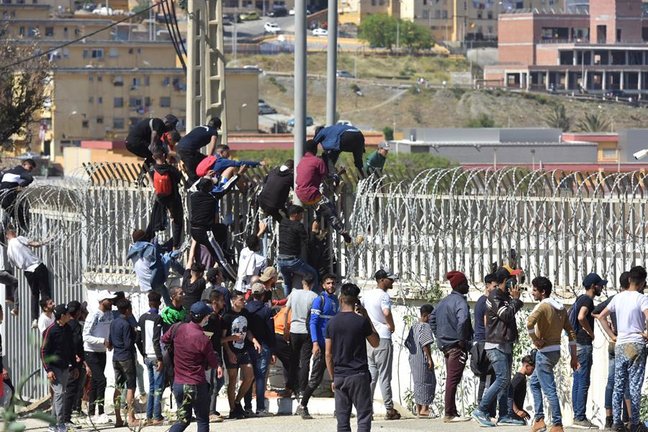 Migrantes escalan la valla en la ciudad norteña de Fnideq en un intento de cruzar la frontera de Marruecos al enclave español de Ceuta, en el norte de África 18 de mayo de 2021. En poco más de 24 horas, un total de casi 8.000 personas han entrado por mar en la ciudad española de Ceuta, situada en la costa norteafricana, y cientos de migrantes siguen intentándolo. Las autoridades españolas han desplegado al ejército para patrullar en la frontera que separa Ceuta en el lado español del lado marroquí, en un intento de controlar esta última oleada de intentos de entrada. (Marruecos, España) EFE/EPA/JALAL MORCHIDI

Traducción realizada con la versión gratuita del traductor www.DeepL.com/Translator