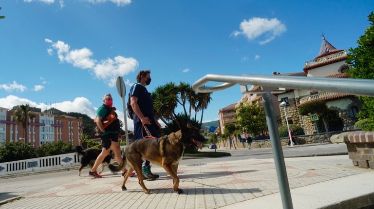 Viandantes con sus perros en Castro Urdiales, municipio que baja de nivel de riesgo. / Hardy