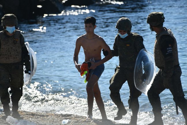 Dos militares del ejército español ayudan a un menor migrante procedente de Marruecos a su llegada a Ceuta