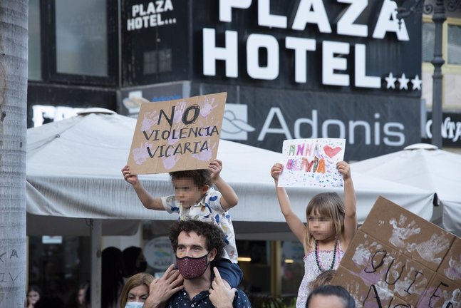 Dos niños con carteles, participan en una concentración feminista en la Plaza de la Candelaria