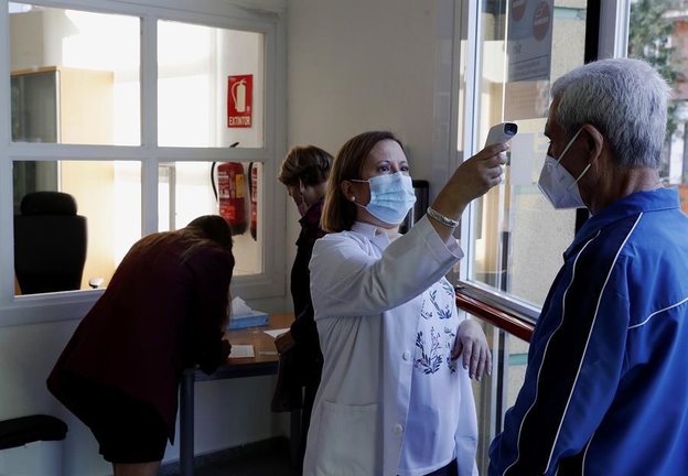 Una trabajadora toma la temperatura a un usuario a las puertas de un centro de mayores, este lunes, día de reapertura de estos centros en la Comunidad de Madrid. EFE/JP Gandul
