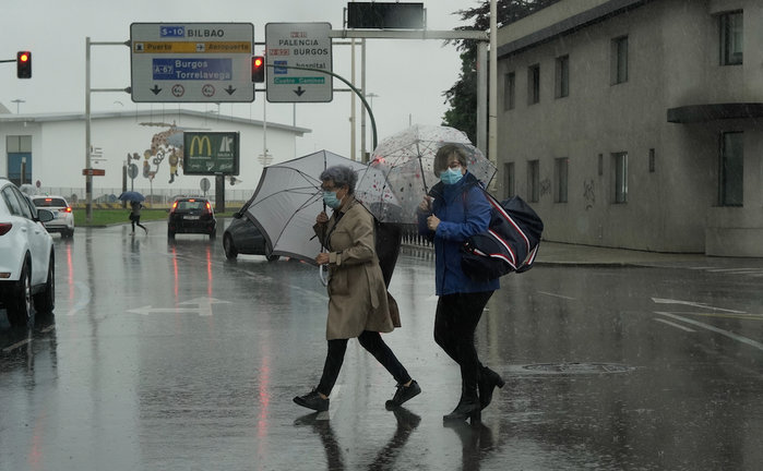 Dos personas cruzan una calle bajo la lluvia en Santander. / HARDY
