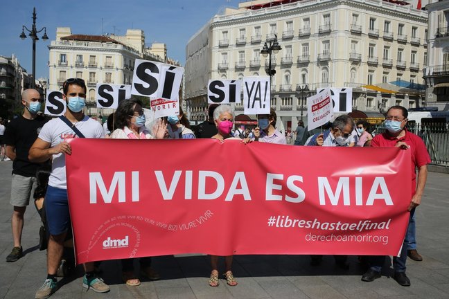 Un grupo de personas se reúne sosteniendo pancartas y carteles durante la concentración de la asociación Derecho a Morir Dignamente (DMD) en la Puerta del Sol