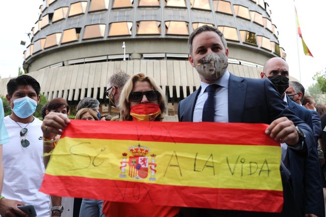 El presidente de Vox, Santiago Abascal, y una mujer sostienen una bandera de España contra la ley de eutanasia, en el Tribunal Constitucional, a 16 de junio de 2021, en Madrid (España).