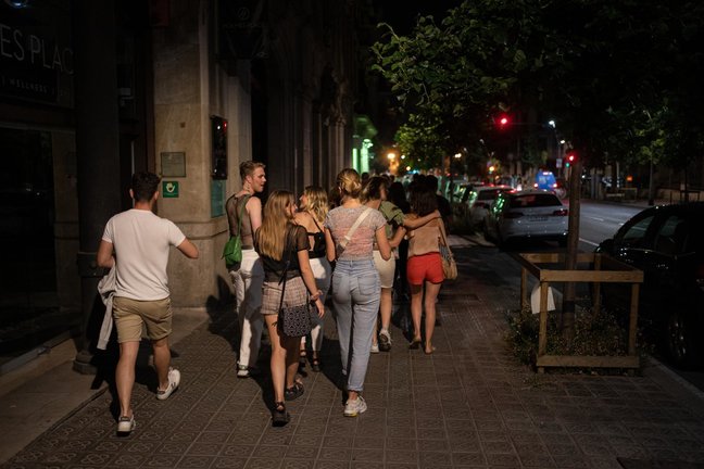 Un grupo de jóvenes pasea por la calle antres de entrar a una discoteca. 27 de junio de 2021, en Barcelona, Catalunya (España). Este jueves 24 de junio, en un Consejo de Ministros extraordinario, el Gobierno de España aprobó que las mascarillas dejasen de ser obligatorias en todo el territorio a partir de hoy, 26 de junio. La jornada coincide con el primer sábado en el que se permite en Catalunya la apertura del ocio nocturno hasta las 3.30 horas en una nueva flexibilización de las restricciones por la pandemia de coronavirus.