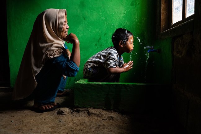 Archivo - Wahyu observa a su hijo Rizki, de 4 años, lavándose la cara en una nueva instalación de agua potable en su casa, en Tlogopakis, Indonesia.