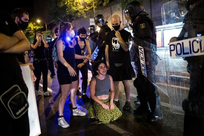 Una joven arrodillada frente a antidisturbios de la Policía Nacional en el barrio de Argüelles tras la concentración por el asesinato del joven Samuel a 5 de julio de 2021 en Madrid (España). 