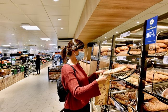 Cliente comprando pan en un supermercado.