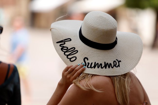 Una mujer se protege del calor con un sombrero. 