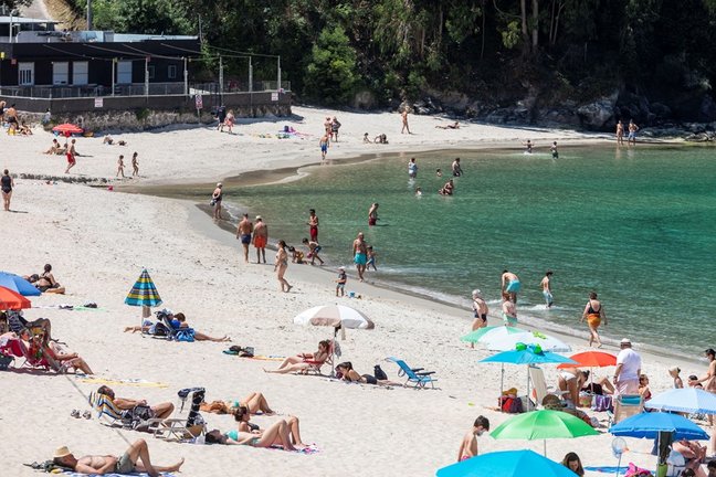 Archivo - Varias personas se bañan y toman el sol en una playa del municipio de Marín, en Pontevedra