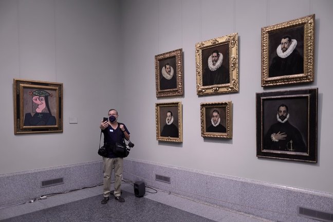 Un hombre se hace una fotografía junto a los retratos de 'El Greco' de Doménikos Theotokópoulos y junto a la obra 'Busto de mujer 43', de Pablo Picasso, el día de la presentación de la instalación en el Museo del Prado.
