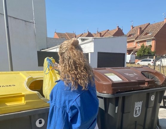 Una mujer deposita envases domésticos en el contenedor amarillo.