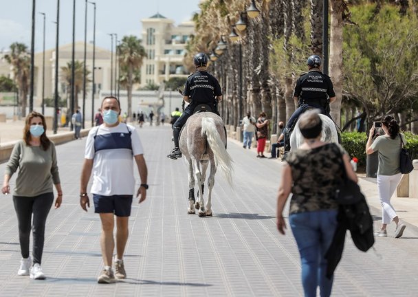 Archivo - Dos policías municipales patrullan a caballo por un paseo marítimo frente a una playa de València, a 26 de mayo de 2021