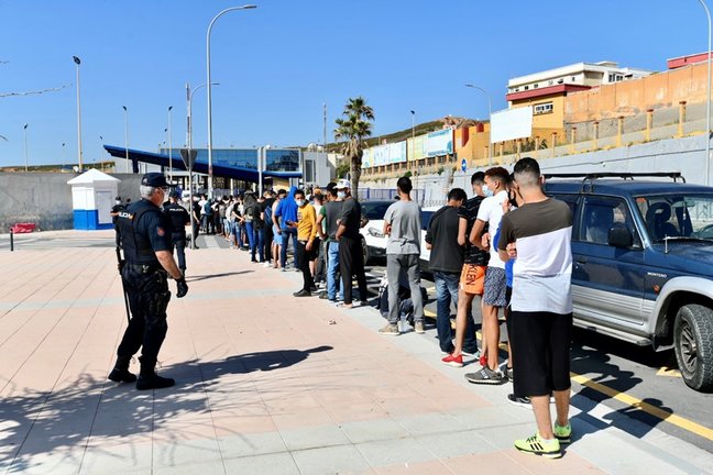 Archivo - Varios migrantes procedentes de Marruecos hacen cola en las puertas de la frontera de Ceuta donde agentes de la Policía Nacional reparten citas para solicitud de asilo, a 2 de junio de 2021, en Ceuta (España). La Policía Nacional gestionó ayer u