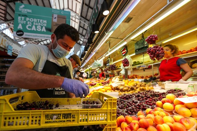 Un hombre trabaja colocando la fruta en una una frutería del Mercado Central de Valencia.