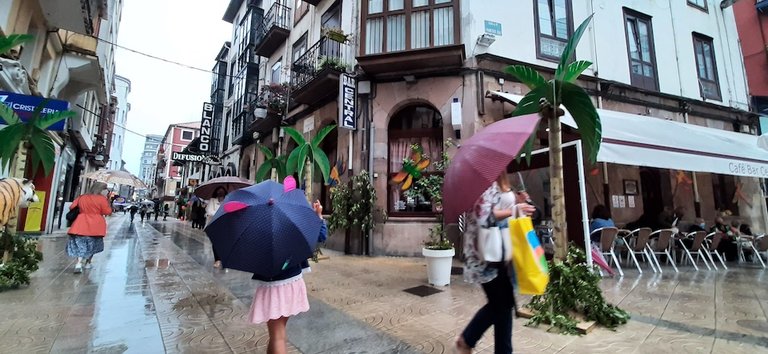 Varias personas con mascarilla y paraguas pasean por la calle Consolación de Torrelavega. / S. Díaz