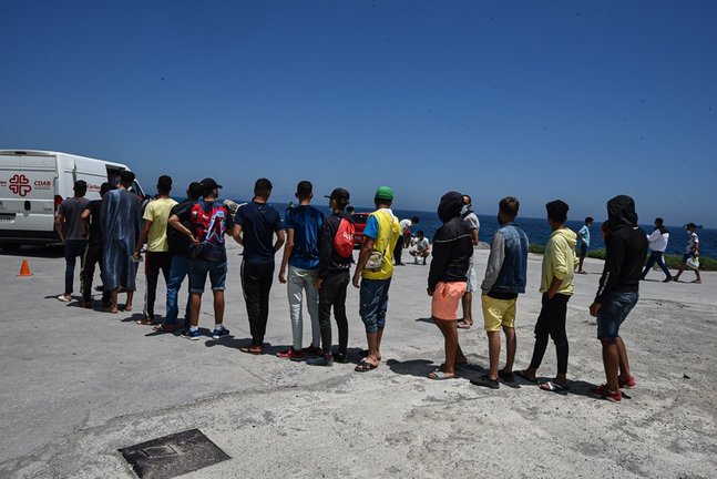 Archivo - Varios migrantes que entraron a Ceuta hacen cola para recibir alimentos de Cáritas Diocesana.