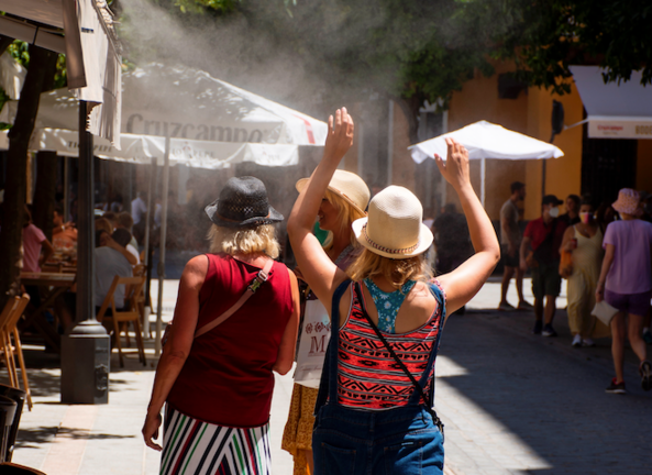 Turistas alivian el intenso calor de estos con los pulverizadores de agua de los restaurantes del centro de Sevilla. EFE/ Raúl Caro.