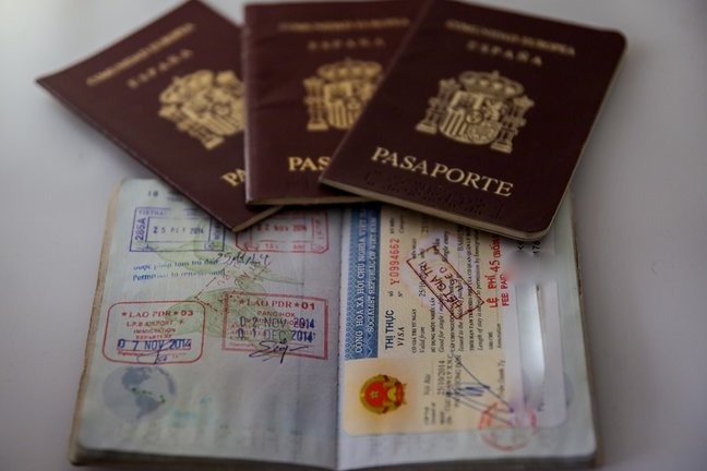 Archivo - Varios pasaportes españoles, uno de ellos abierto, sobre una mesa.