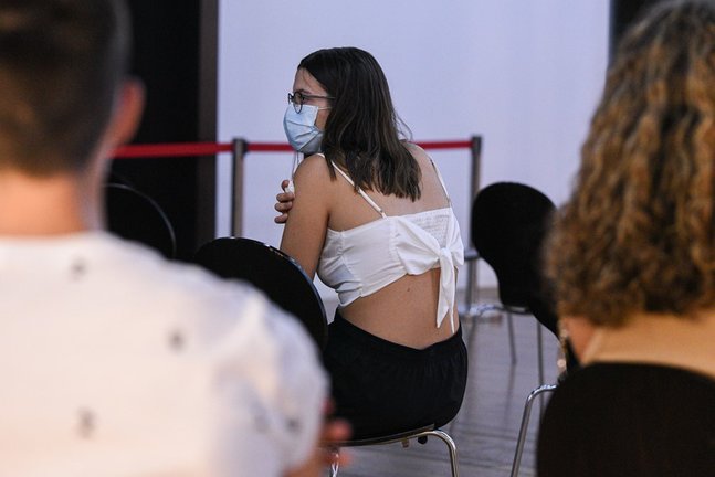 Una adolescente espera en una sala, después de recibir la primera dosis de la vacuna Pfizer en el punto de vacunación de Xátiva, situado en el Hogar de los Jubilados, a 10 de agosto de 2021, en Xátiva, Valencia, Comunidad Valenciana (España).