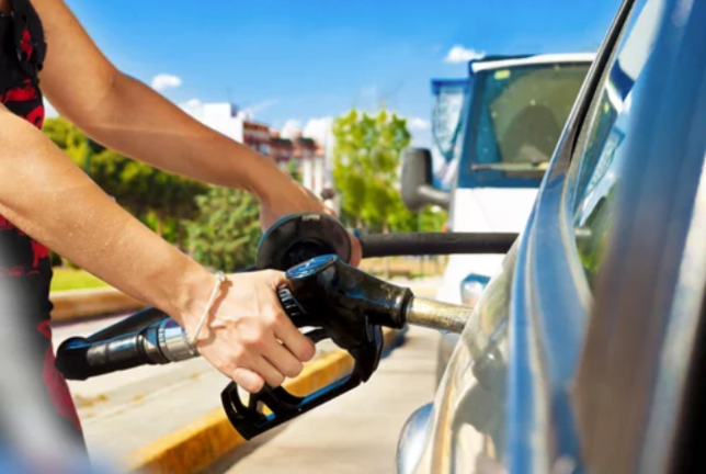 Una mujer pone gasolina a su vehículo en una gasolinera.