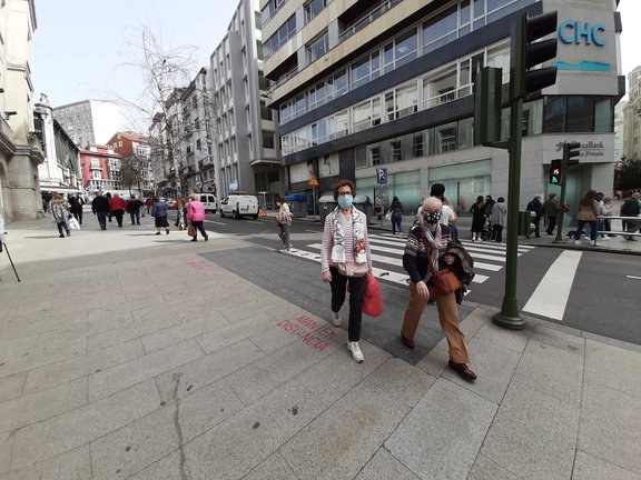 Varias personas con mascarilla cruzan una calle junto al Ayuntamiento de Santander. / S. Díaz