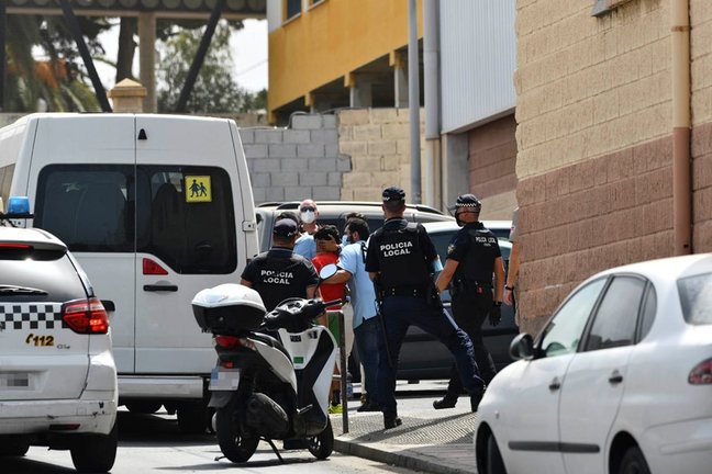 Varios agentes y vehículos de la Policía Local de Ceuta acompañan a menores no acompañados hacia una furgoneta, en las inmediaciones del Polideportivo Santa Amelia, donde fueron acogidos 250 de los 800 menores que llegaron a Ceuta el pasado mes de mayo,