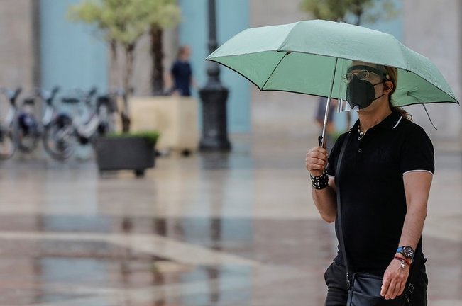 Una persona sostiene un paraguas mientras llueve, a 26 de julio de 2021, en Valencia, Comunidad Valenciana, (España). Para esta jornada, con nivel máximo naranja, se espera cielo nuboso que tenderá a intervalos nubosos al final y viento de componente este