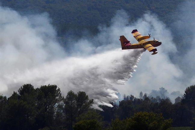 Un avión de extinción de incendios lanza agua en el lugar de un incendio forestal en la localidad de Gonfaron, cerca de Saint-Tropez. EFE/EPA/GUILLAUME HORCAJUELO