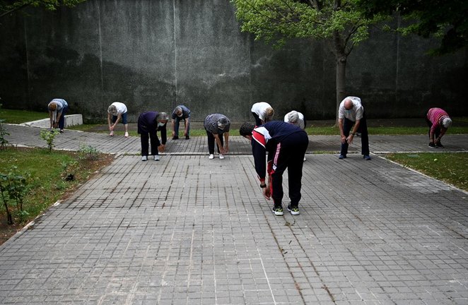 Archivo - Un grupo de ancianos realiza ejercicio en el jardín de un centro de día de personas mayores 